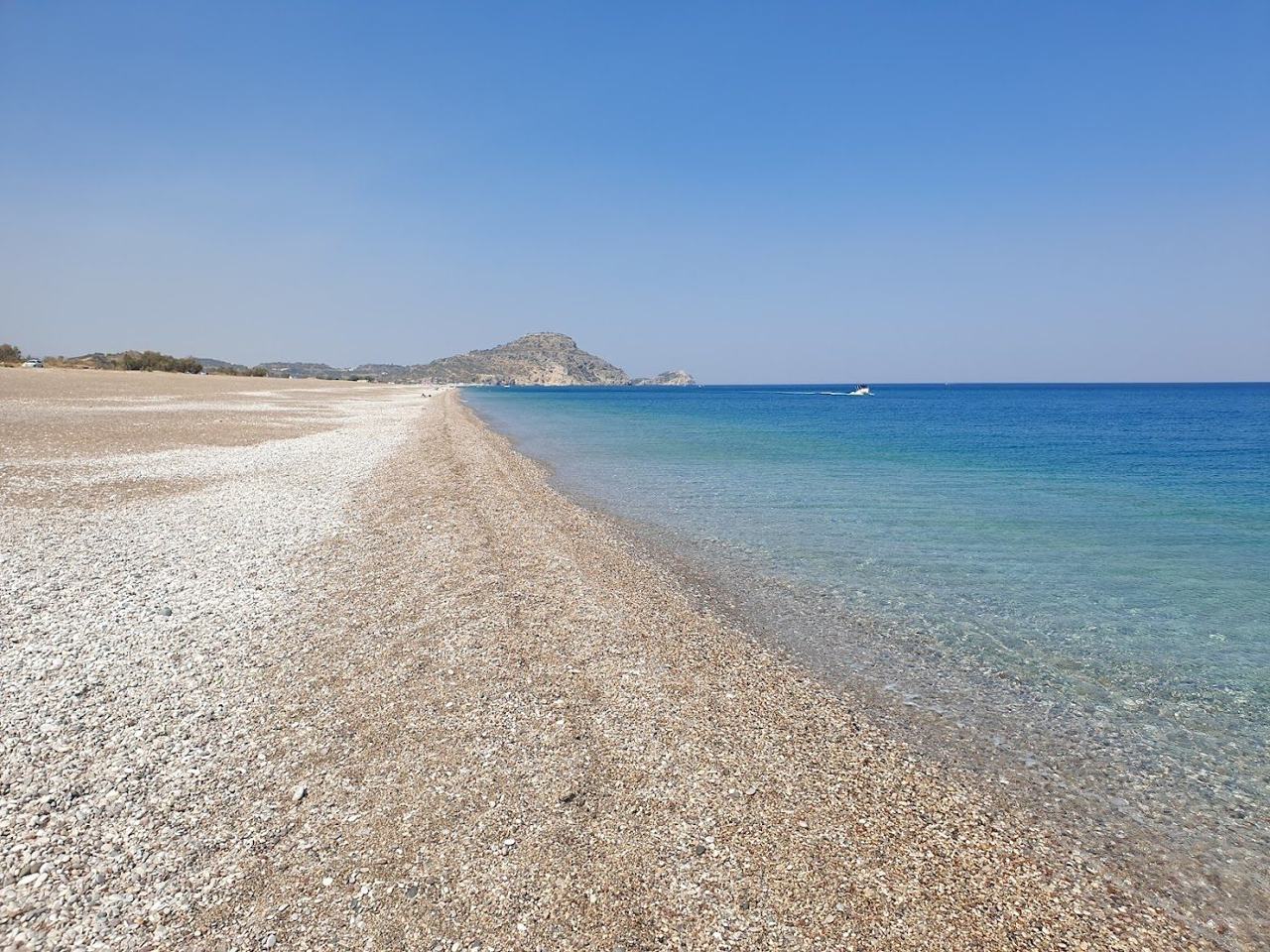 Clear blue water along the long quiet pebble and sand shore of Afandou beach beside the golf course on the east coast of Rhodes