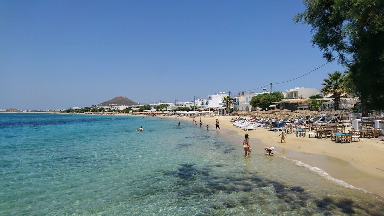 The sheltered sand and calm clear water of Agia Anna beach beside its fishing port in Naxos