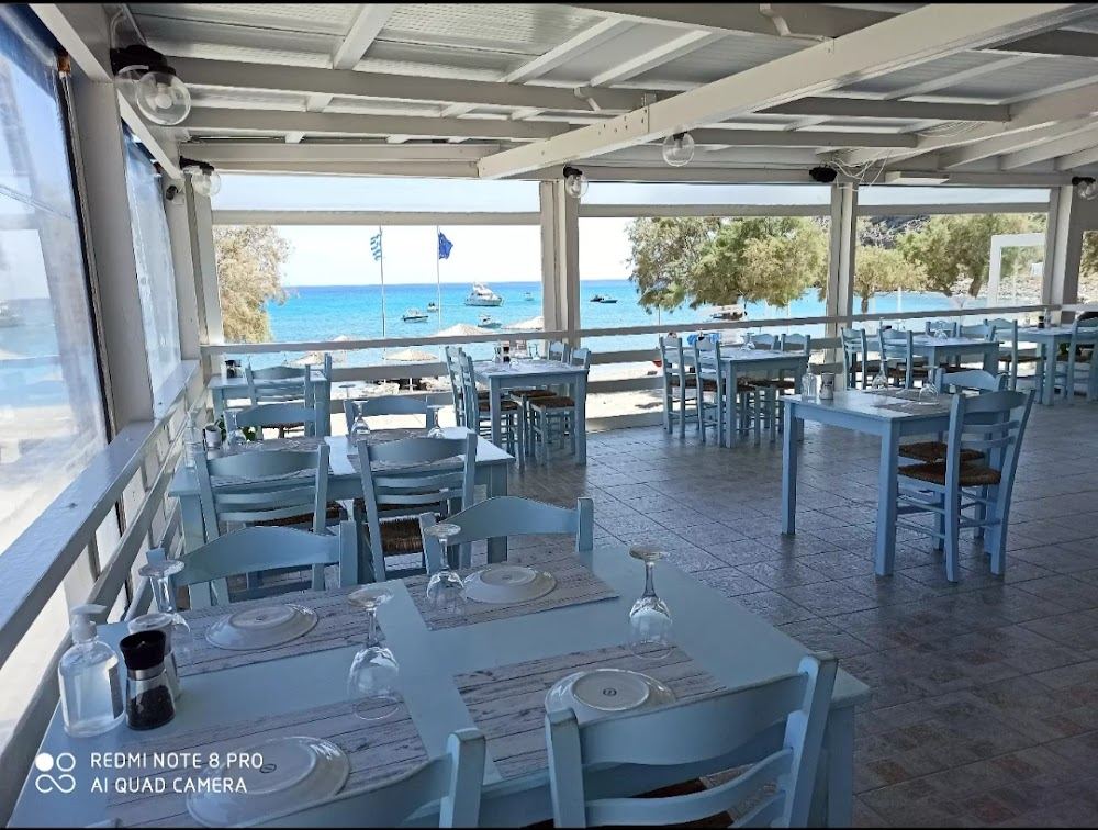 A fish taverna and tables above the sand and pebble shore at Agia Kyriaki beach on the south coast of Milos