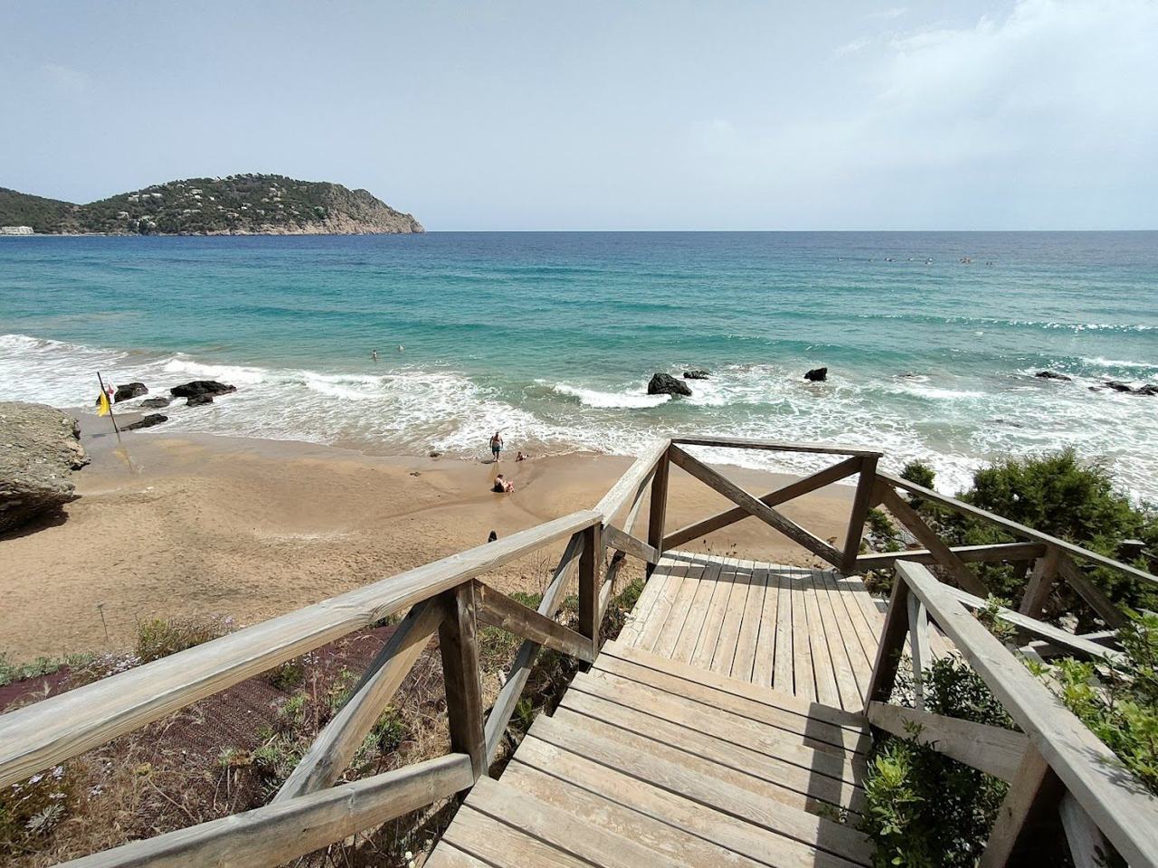 The cliff backed dark sand and open sea of Aguas Blancas reached by a steep stairway in Ibiza