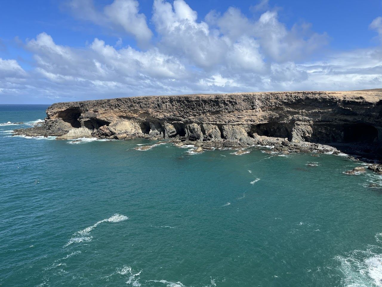 Wild black volcanic sand beach below dark cliffs and Atlantic surf at Ajuy on the west coast of Fuerteventura