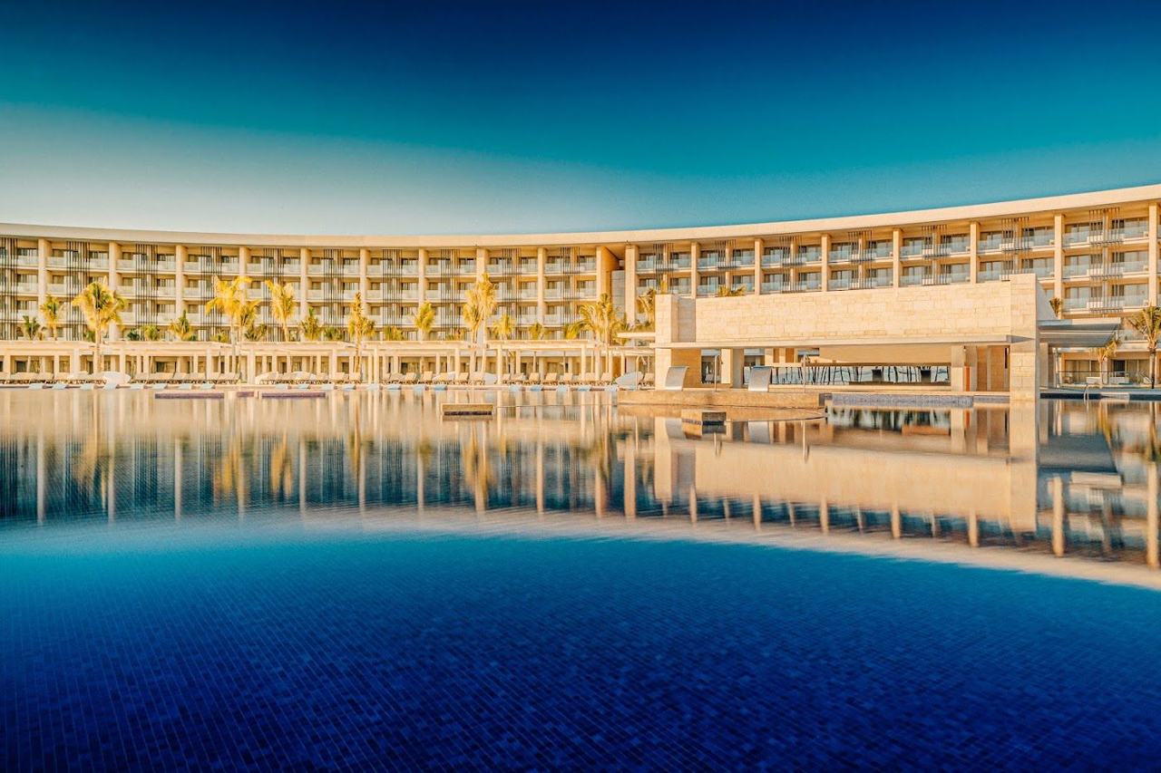 Soft white sand and warm Caribbean water below a stylish hotel on the Riviera Maya