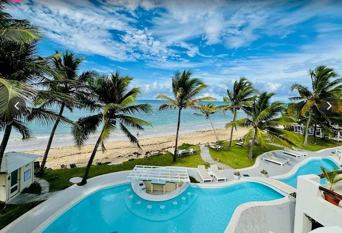 A long palm backed white sand beach below a resort in Punta Cana