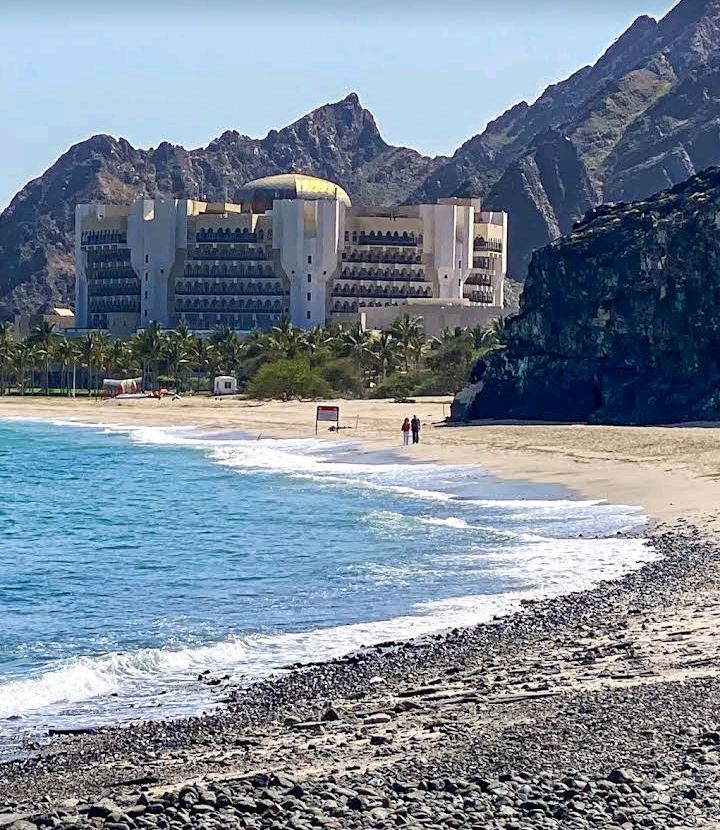 Calm mountain backed bay and pale sand at Al Bustan Beach south of Muttrah in Muscat