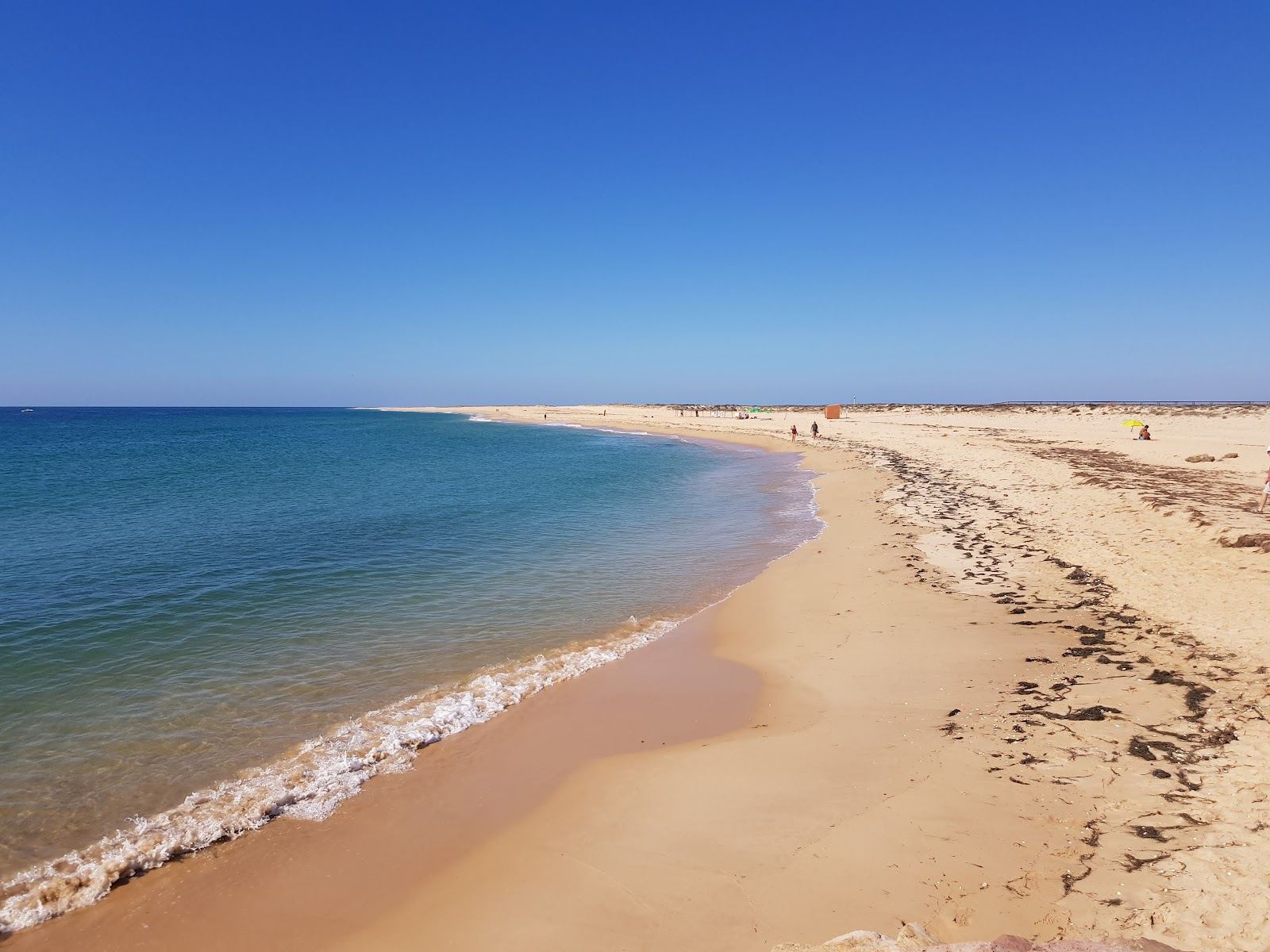 Wide pale sand and clear shallow water on Ilha Deserta barrier island off Faro in the Algarve