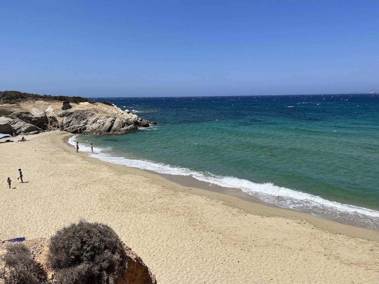 A small turquoise cove framed by cedar trees and dunes at Alyko in Naxos