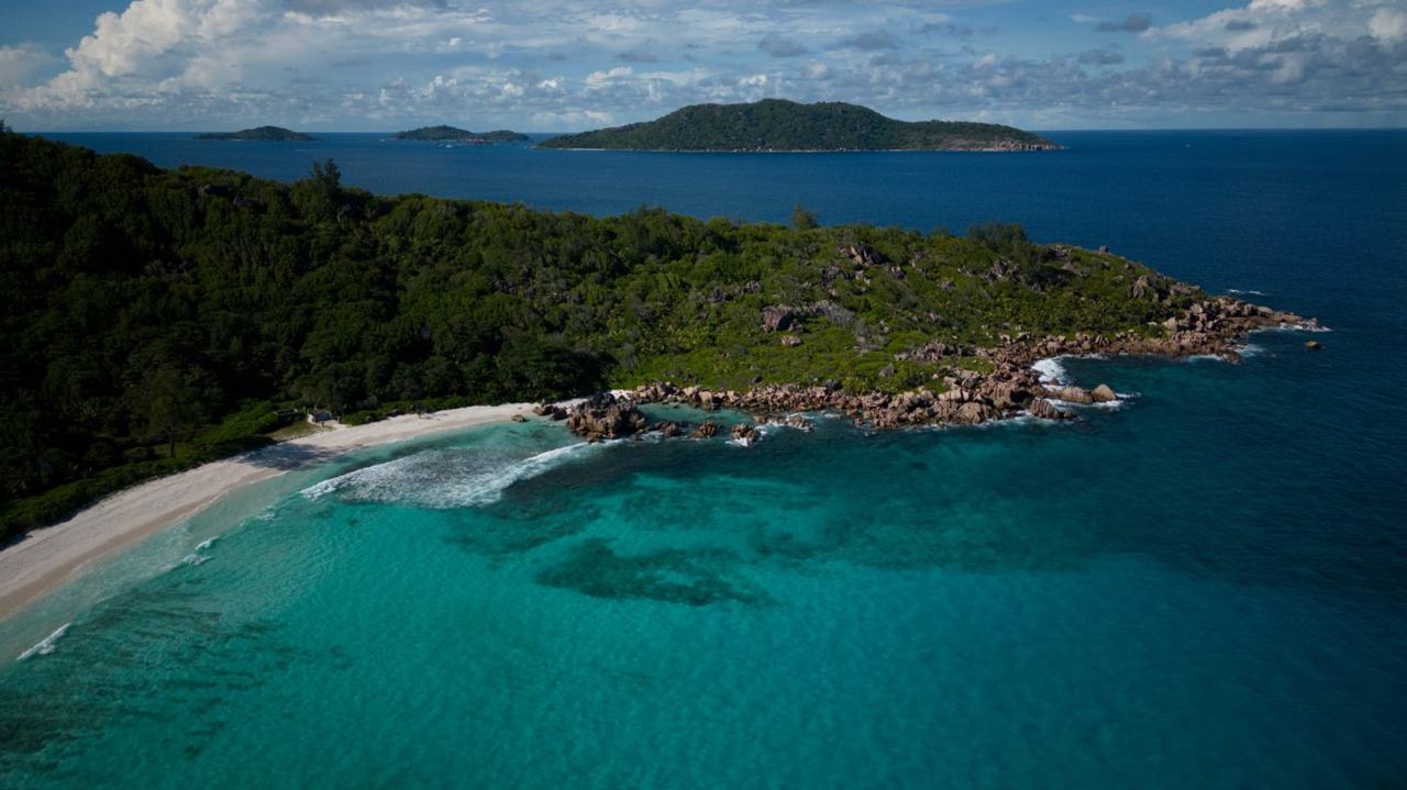 Open sea and palm backed sand at Anse Cocos reached by the coast path on La Digue