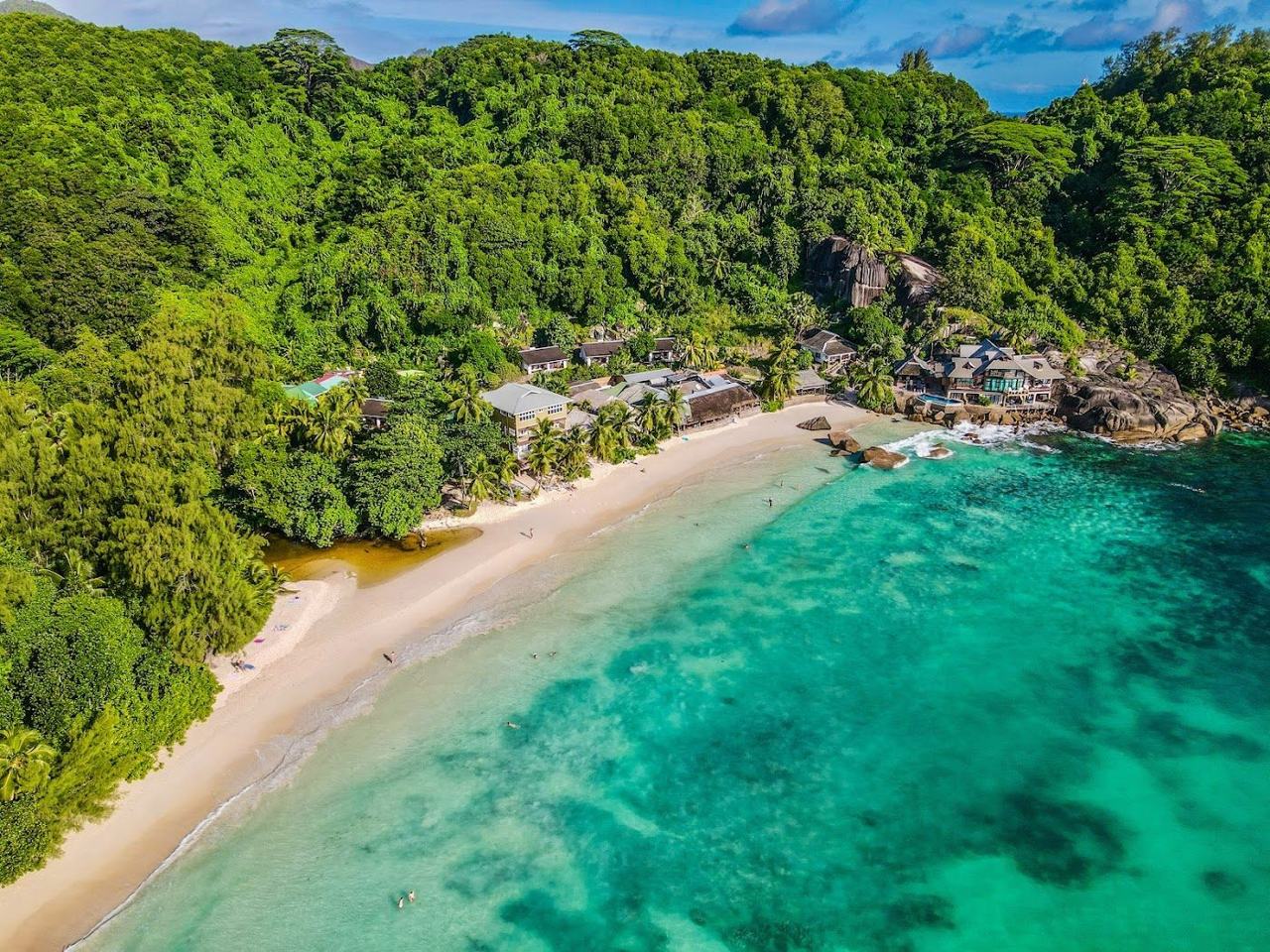 Curving golden sand and palms at Anse Takamaka on the south west coast of Mahe in Seychelles