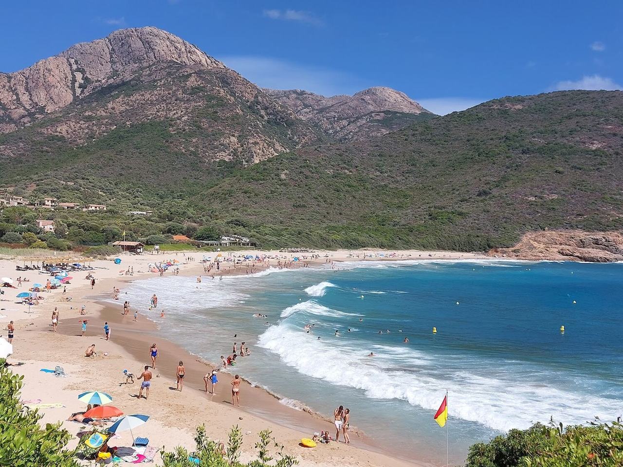 Wide sandy curve of Arone Beach on the west coast of Corsica with maquis hills behind