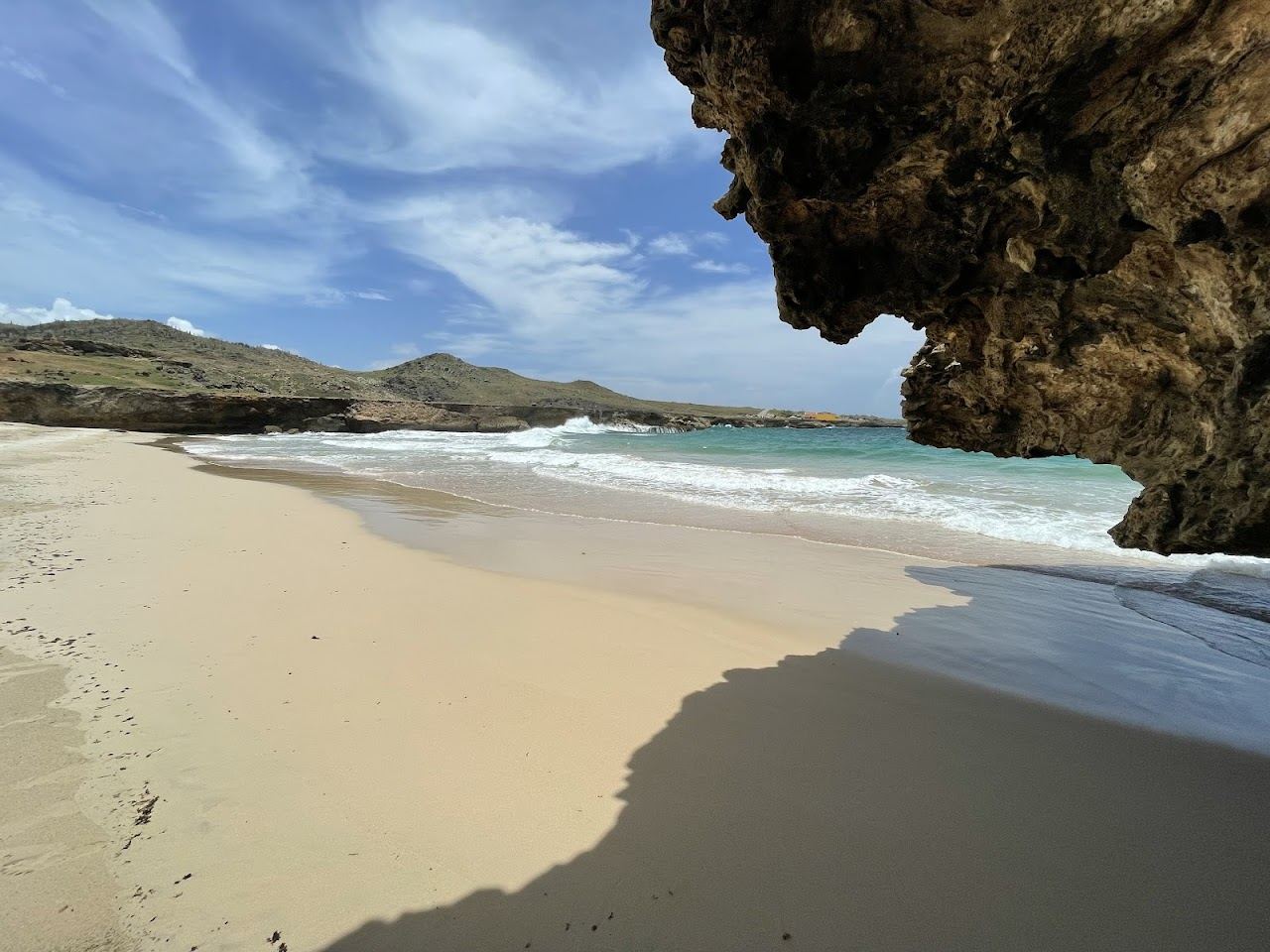 Dramatic coral stone cliffs and Atlantic surf framing the wild bay of Andicuri Beach on the north coast of Aruba
