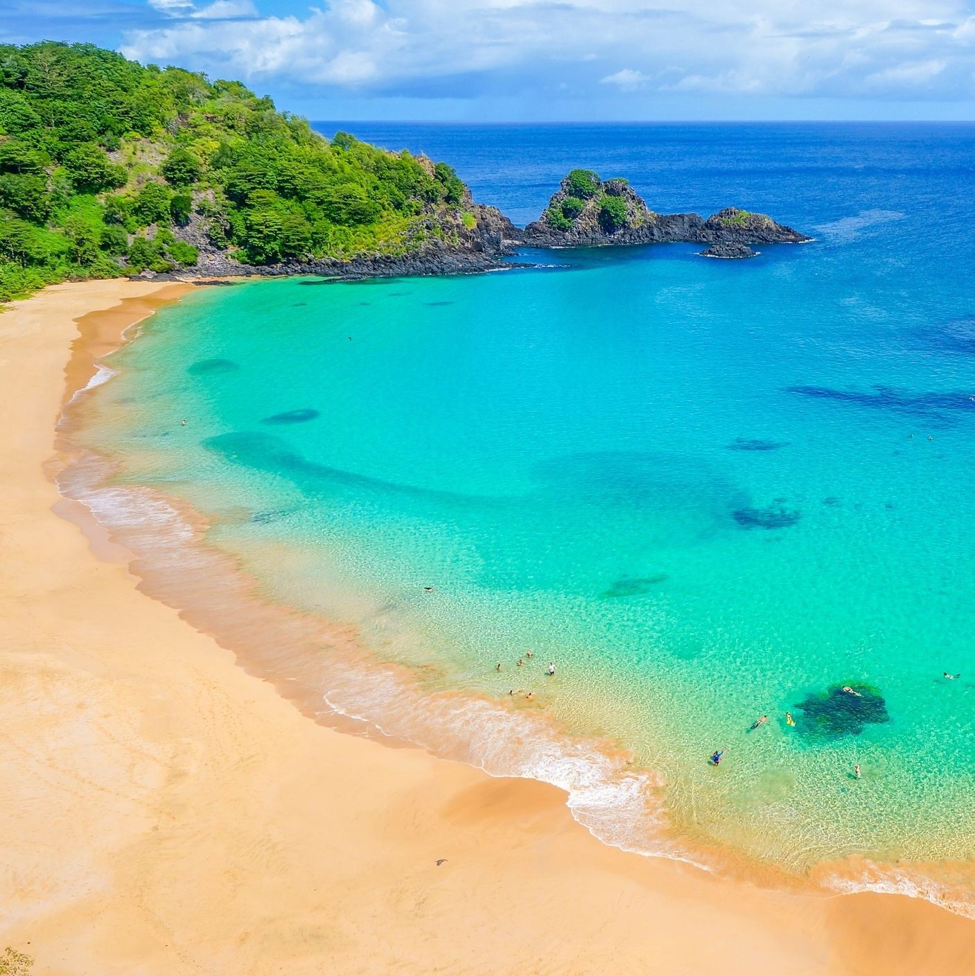 Golden sand and clear water framed by tall green cliffs at Baia do Sancho on Fernando de Noronha