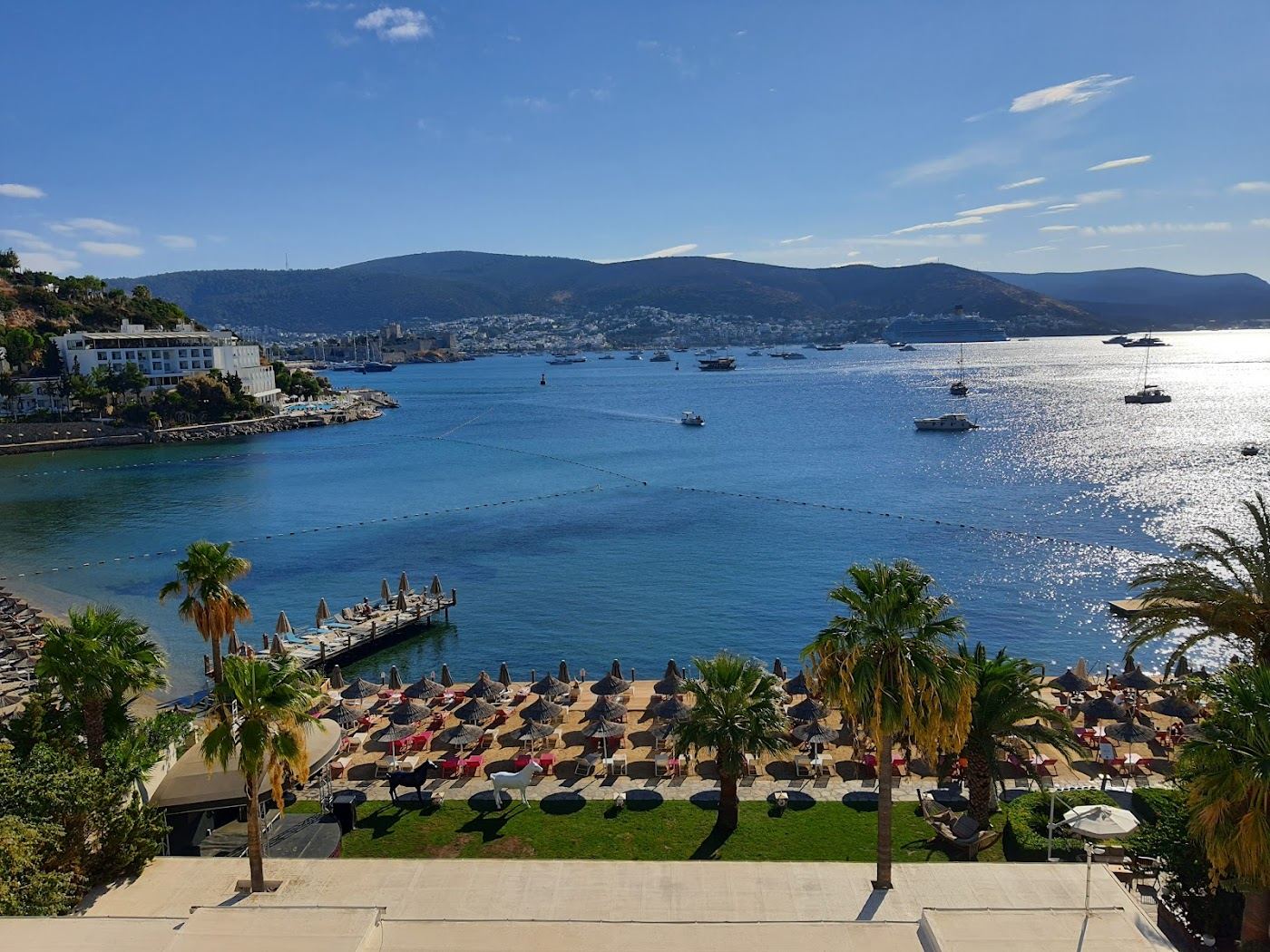 Bardakci bay just west of Bodrum town with calm water, beach club platforms and the hillside hotels above in Turkey