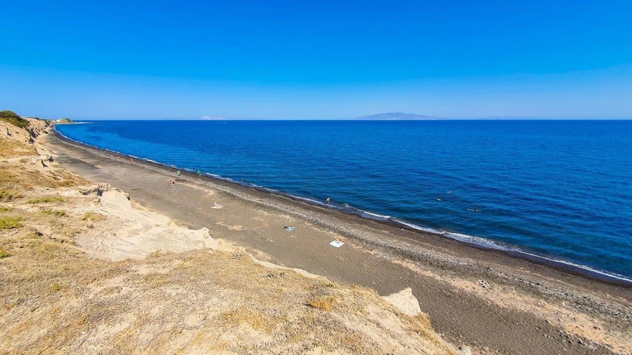 The undeveloped dark sand and volcanic cliffs of Baxedes Beach on the north coast of Santorini