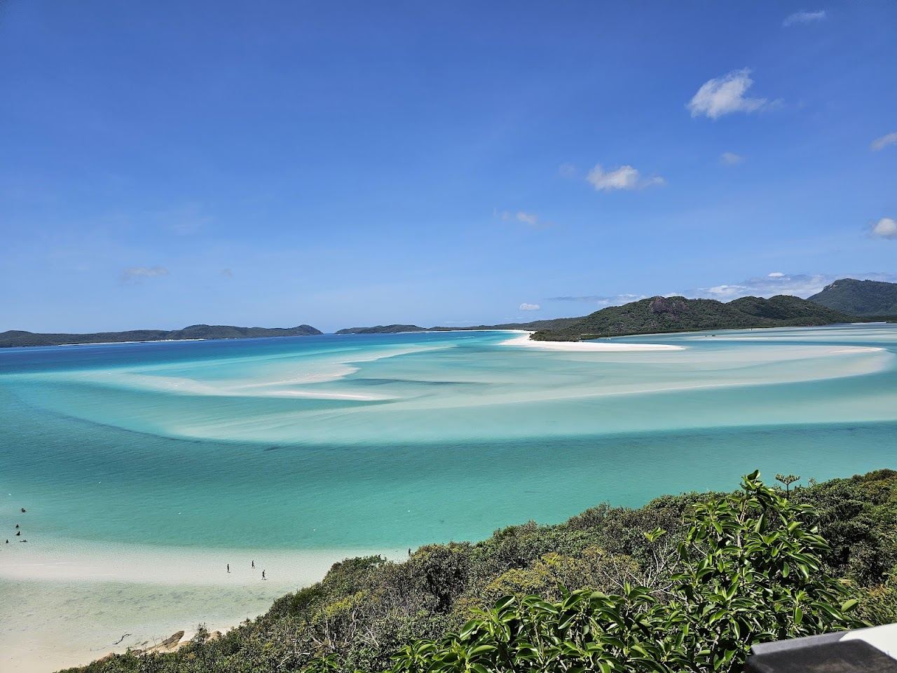 Quiet boulder dotted sand and clear water at Betty's Beach on Whitsunday Island in the Whitsundays