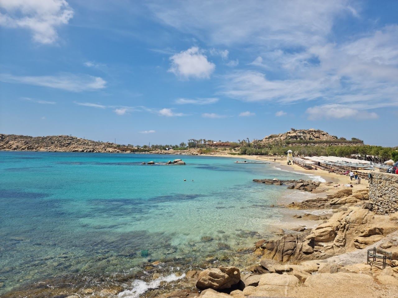 Rocky headland and sunset crowd above the cove at Paraga on Mykonos