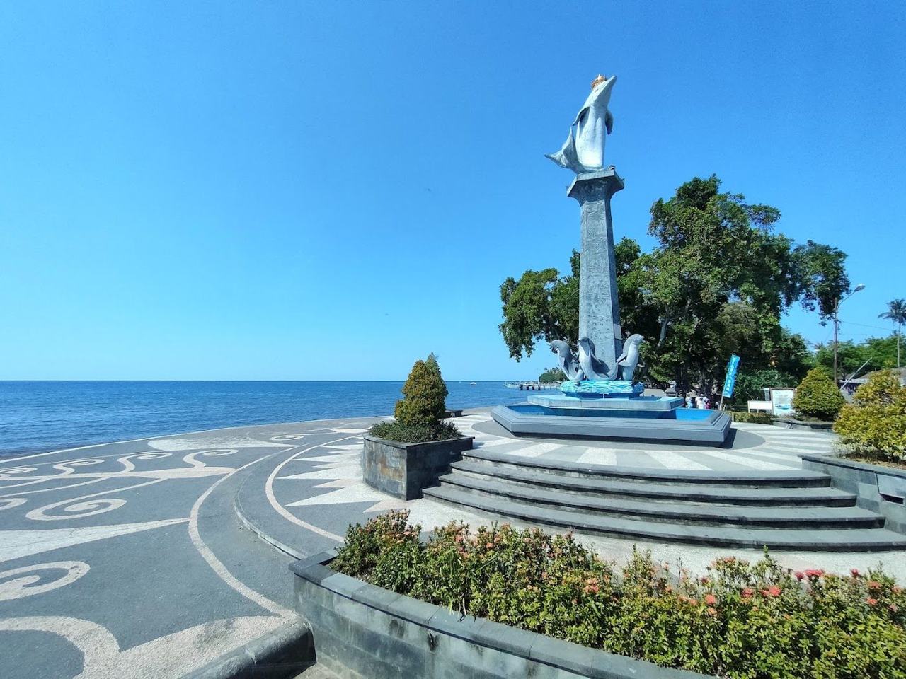 Calm grey black sand on Bali's quiet north coast, known for sunrise dolphin trips and gentle water.