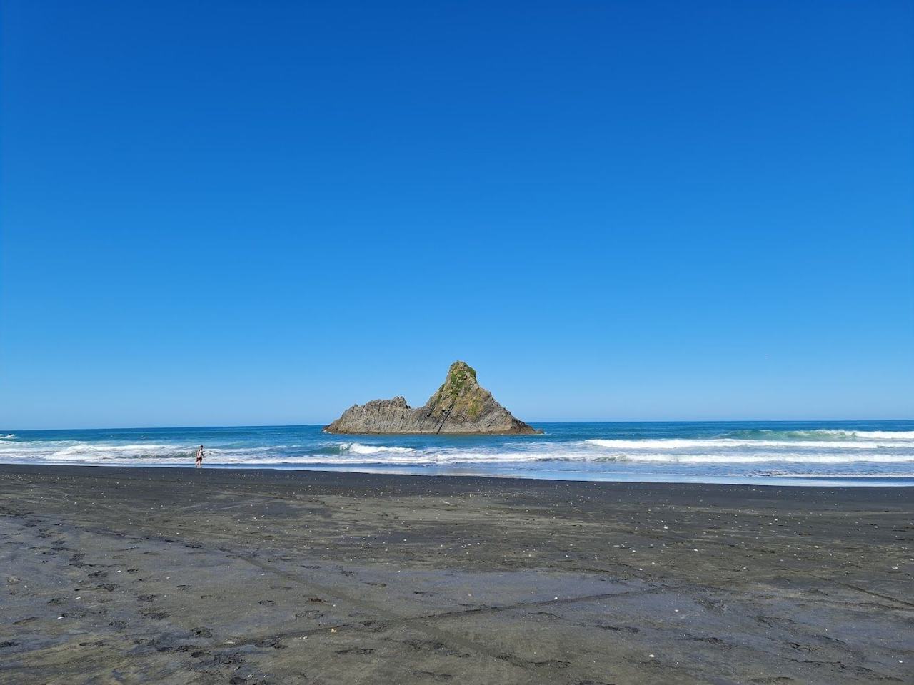 Wild, windswept black sand backed by cliffs and dunes on Auckland's rugged west coast.