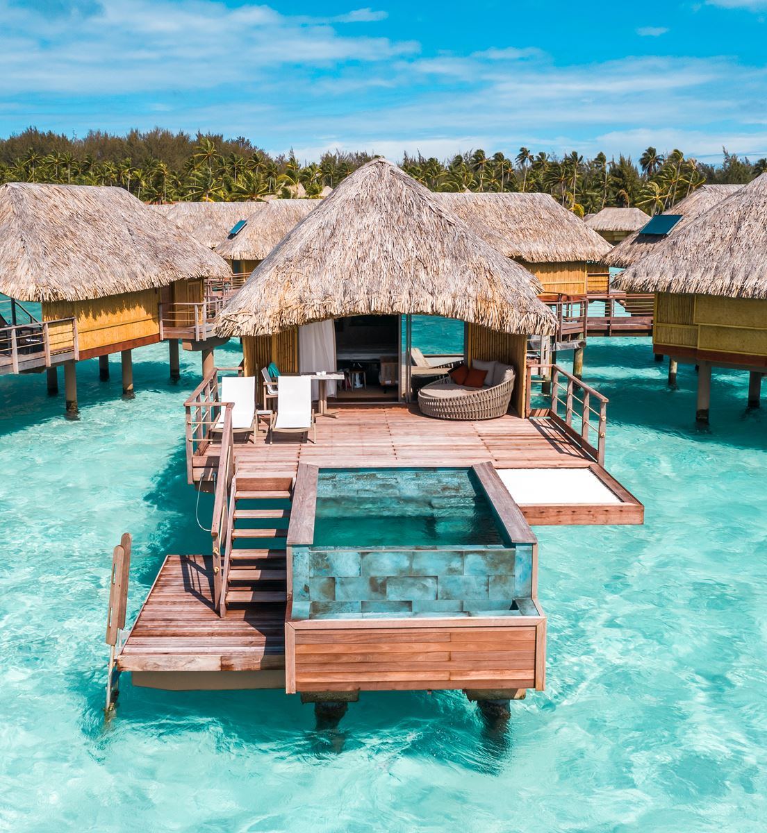 Overwater bungalows over the turquoise Bora Bora lagoon below Mount Otemanu