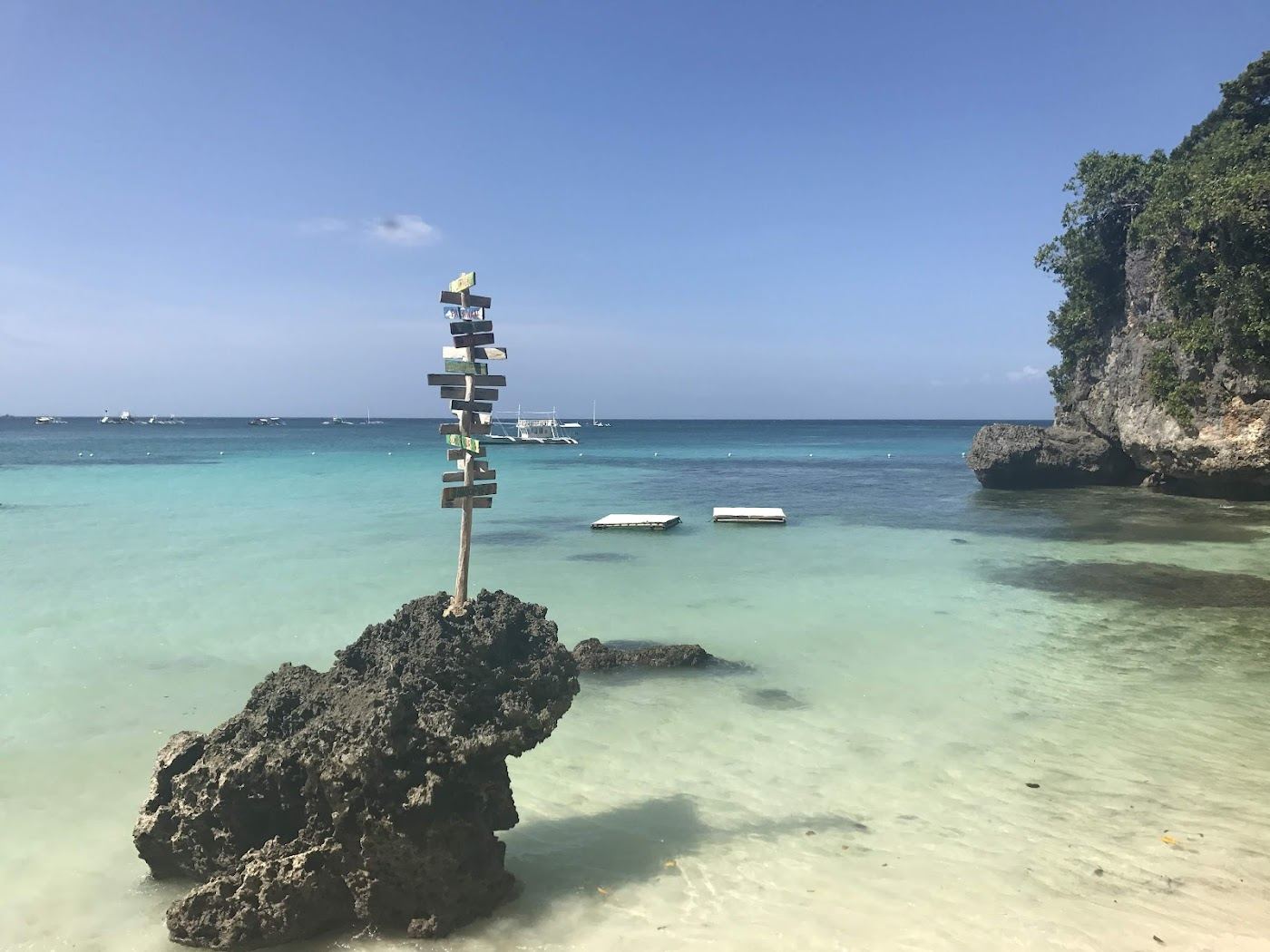 Small secluded cove with calm clear water framed by cliffs and greenery at Balinghai Beach in northern Boracay