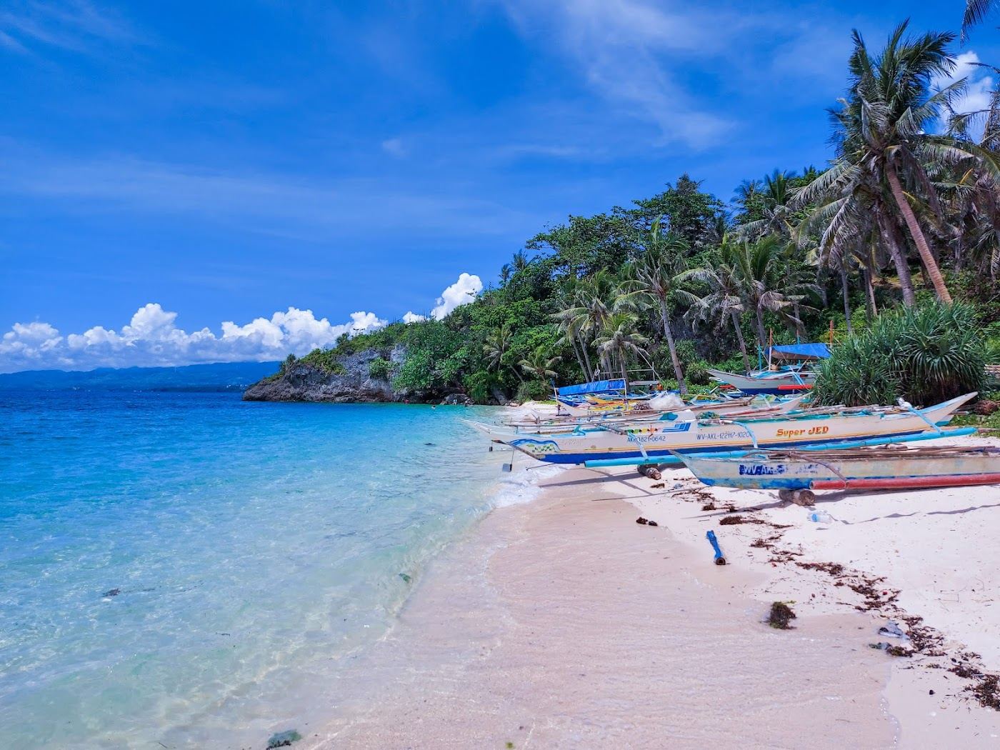 Soft white sand, clear water and a forest backdrop at secluded Ilig Iligan Beach in northeast Boracay