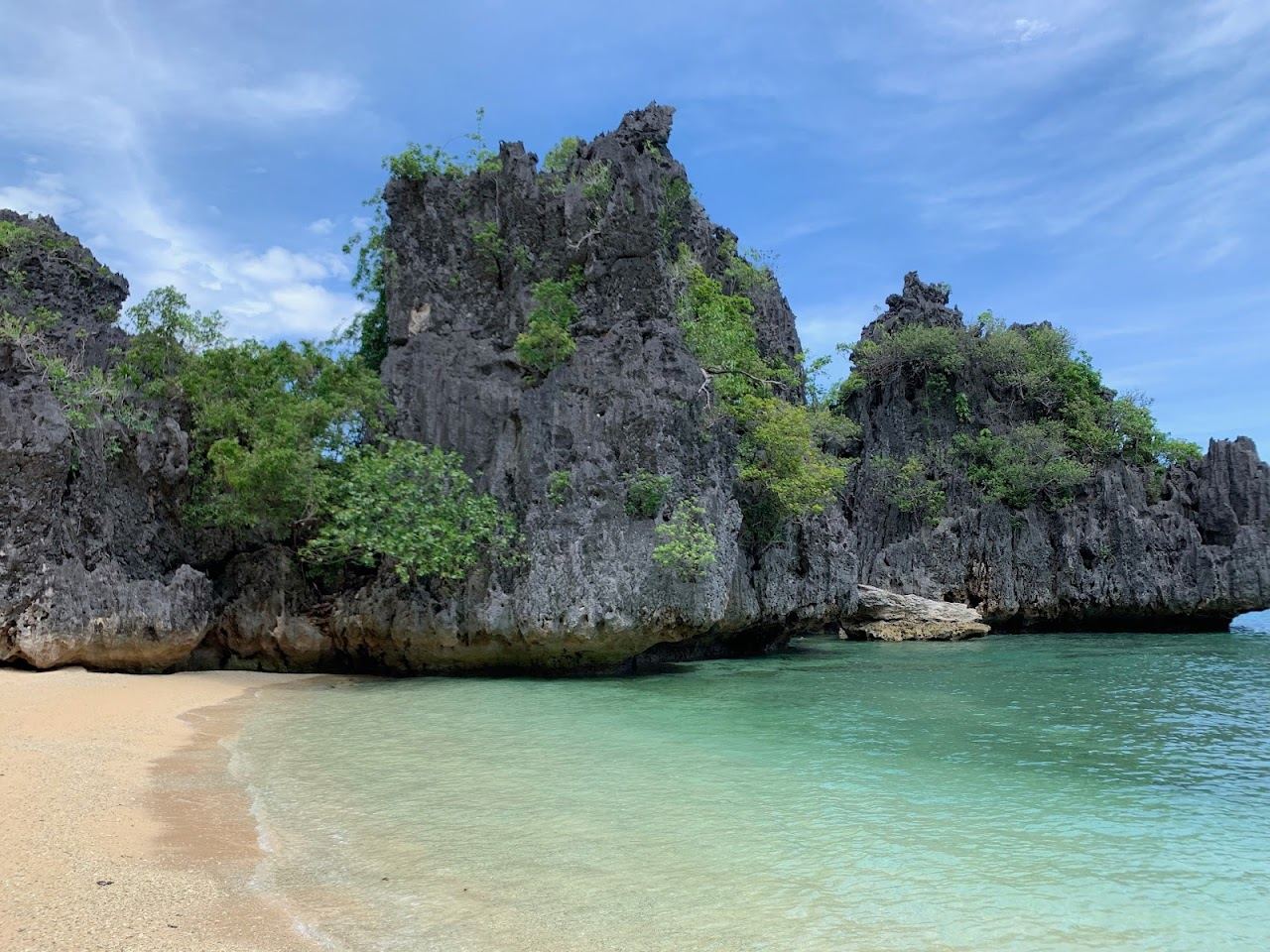 Secluded cove with clear calm water enclosed by rock formations at Lapuz Lapuz Beach in Boracay
