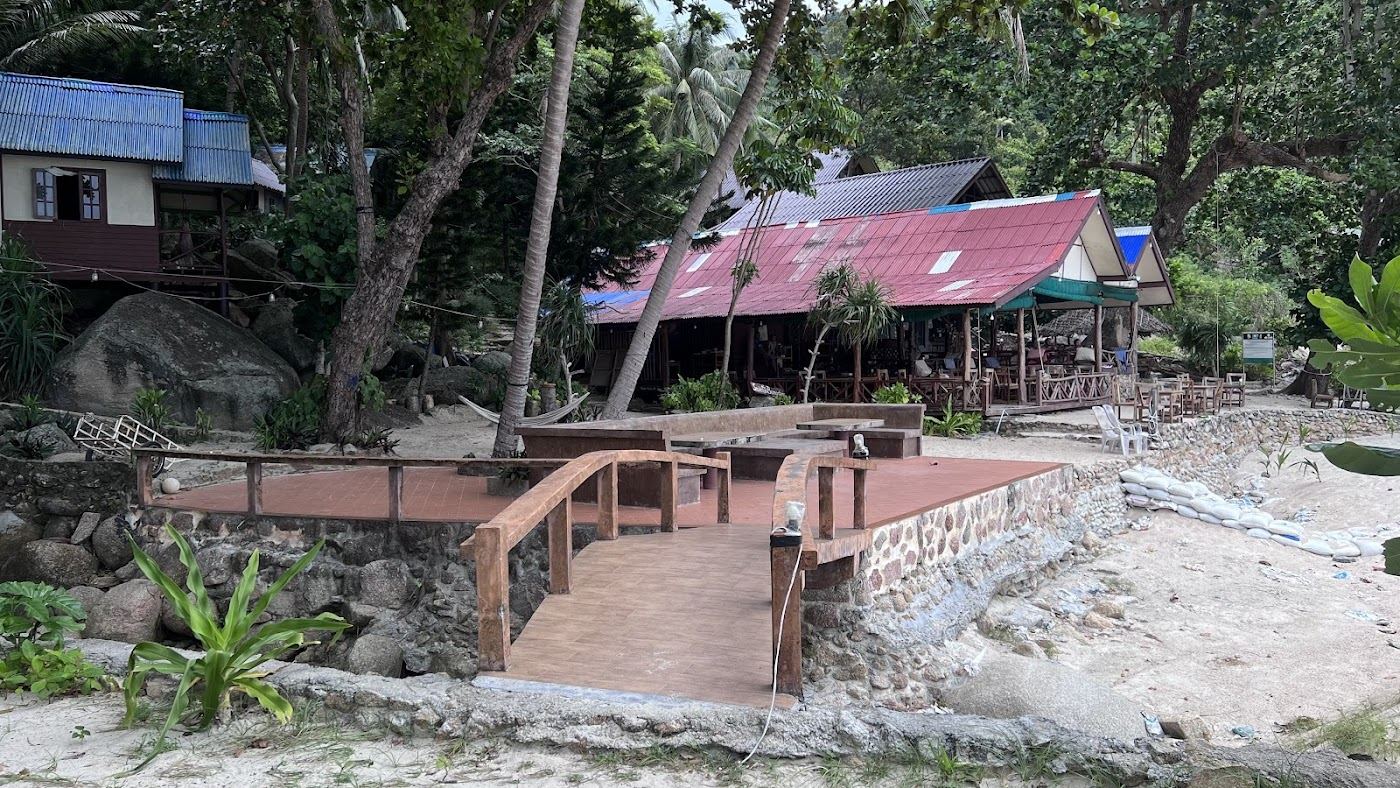 A simple bungalow beach restaurant under the trees on the sand at Bottle Beach in Koh Phangan