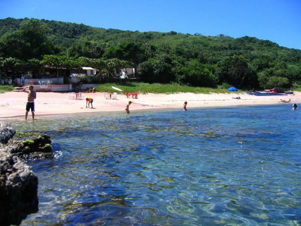 Warm evening light over the sheltered cove at Praia do Forno in Buzios
