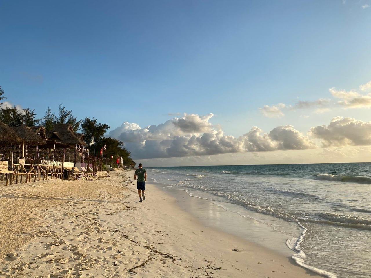 Wide white sand, leaning palms and a calm turquoise lagoon along the quiet village shore at Bwejuu on the southeast coast of Zanzibar