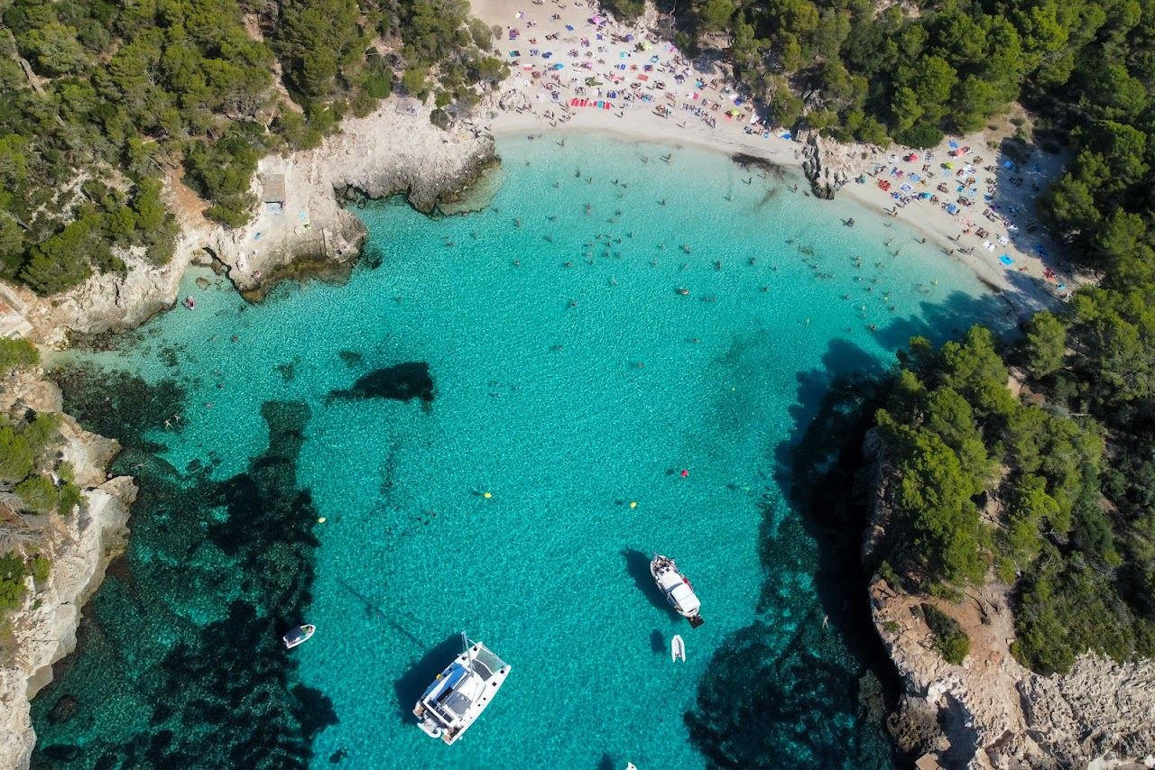 Sheltered white sand and clear turquoise water in the cove of Cala Turqueta in Menorca