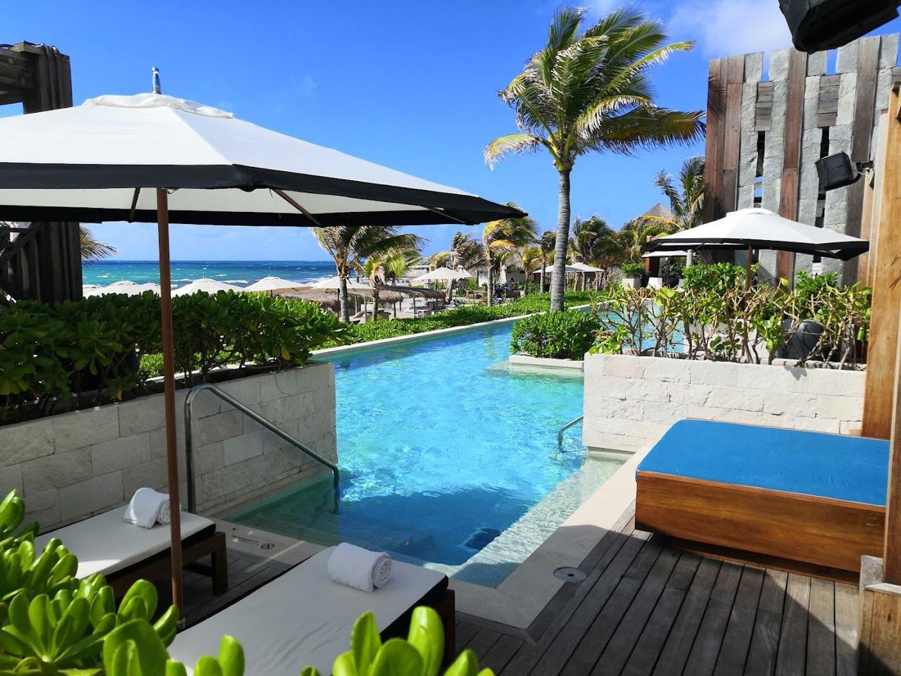 A large resort beach club with pools and palms on the white sand of the Riviera Maya