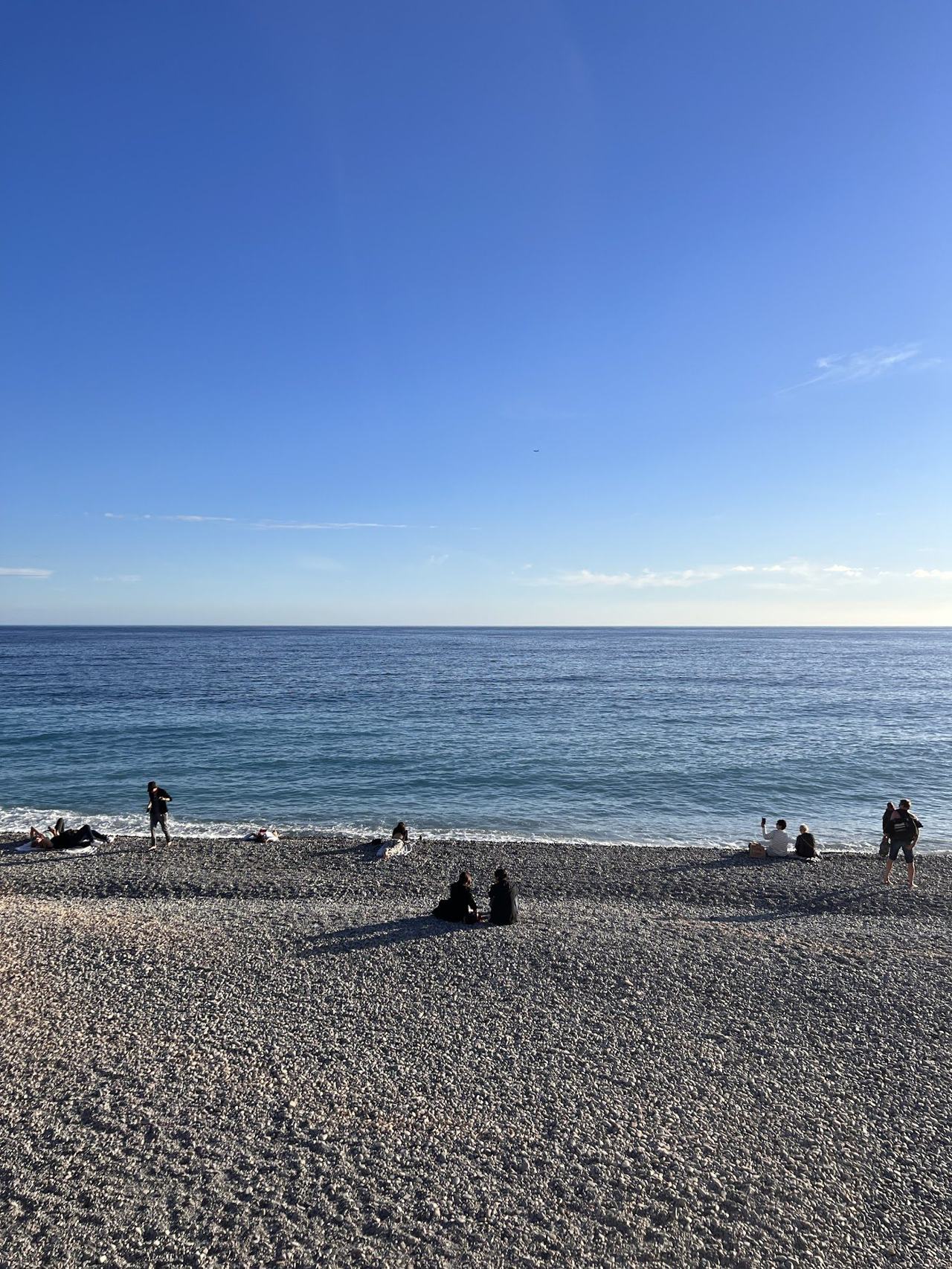 Local pebble beach and open clear water at Plage de Carras on the western Nice promenade