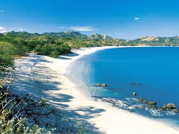 The crushed shell sand and calm green water of Playa Conchal in Guanacaste, Costa Rica