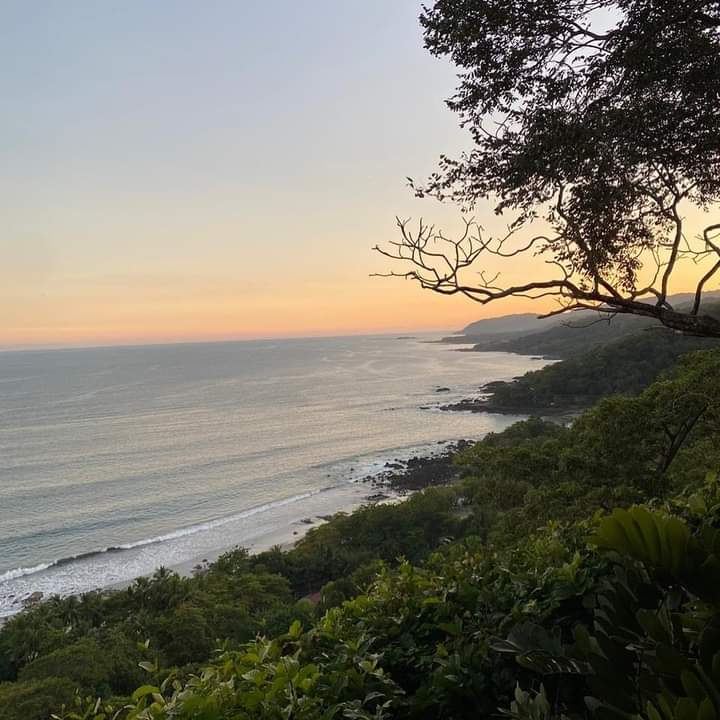 Wide grey gold sand and a long surf break under low sun at Santa Teresa on the Nicoya Peninsula, Costa Rica