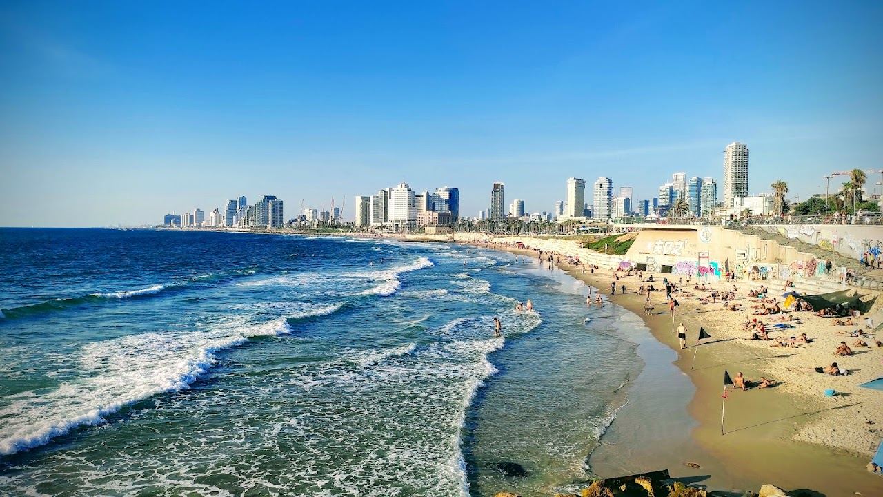 The wide sand and grassy park of Charles Clore beach in Tel Aviv with Jaffa in the distance