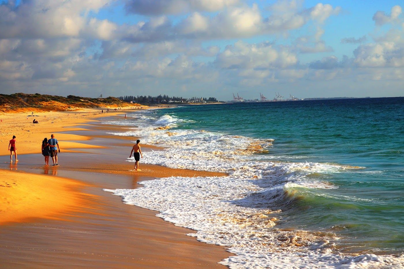 The wide sand, grassed foreshore and gentle morning water of City Beach in Perth, Western Australia
