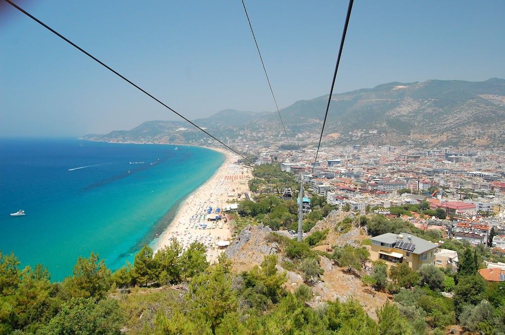 Sunbeds and umbrellas on the pale sand of Cleopatra beach in Alanya with the castle peninsula behind