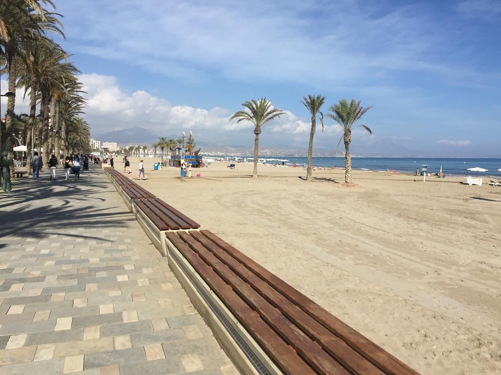 Balinese beds and sunbeds on the sand at a Costa Blanca beach club above clear Mediterranean water