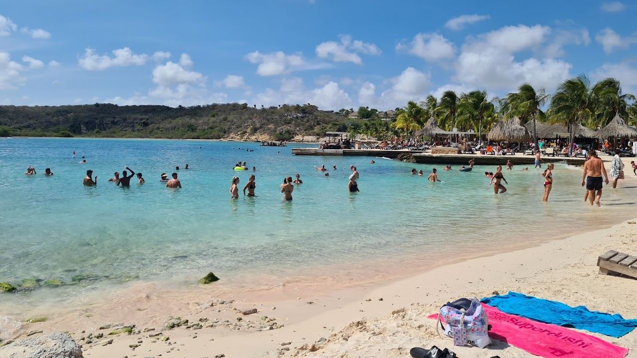 Clear turquoise water and groomed sand framed by terraces at Jan Thiel Beach in Curacao