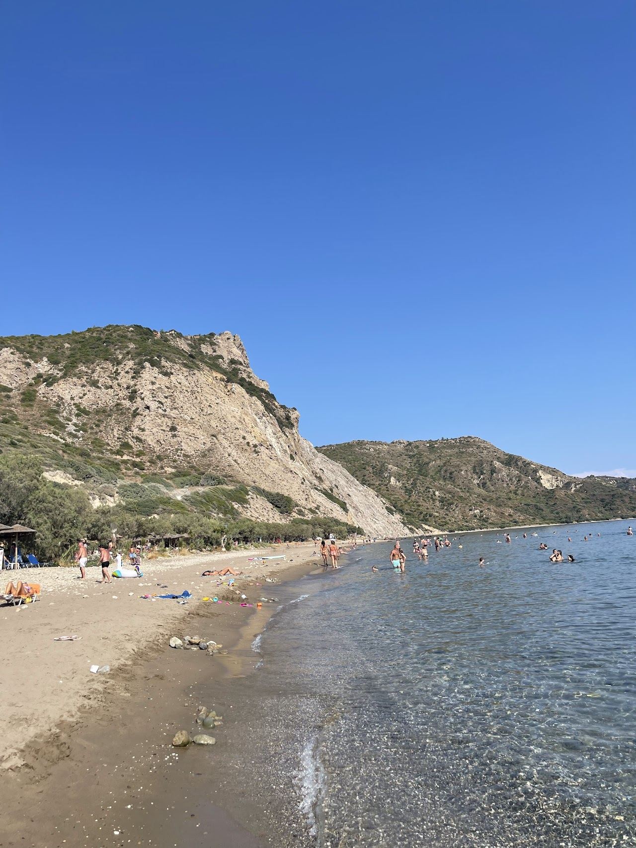 The wide sand and clear shallow water of Dafni beach backed by green hills on the Vassilikos coast of Zakynthos