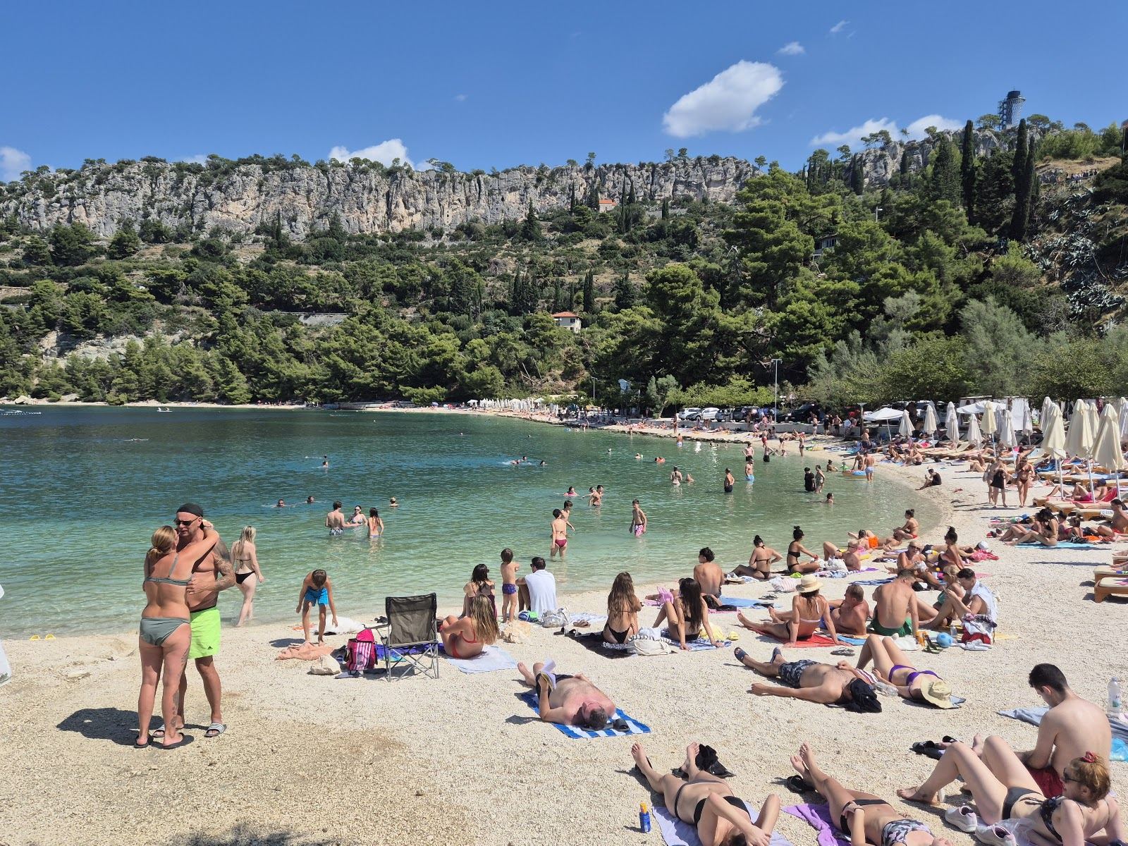 Pine shaded pebble cove with clear water at Kasjuni Beach below Marjan in Split