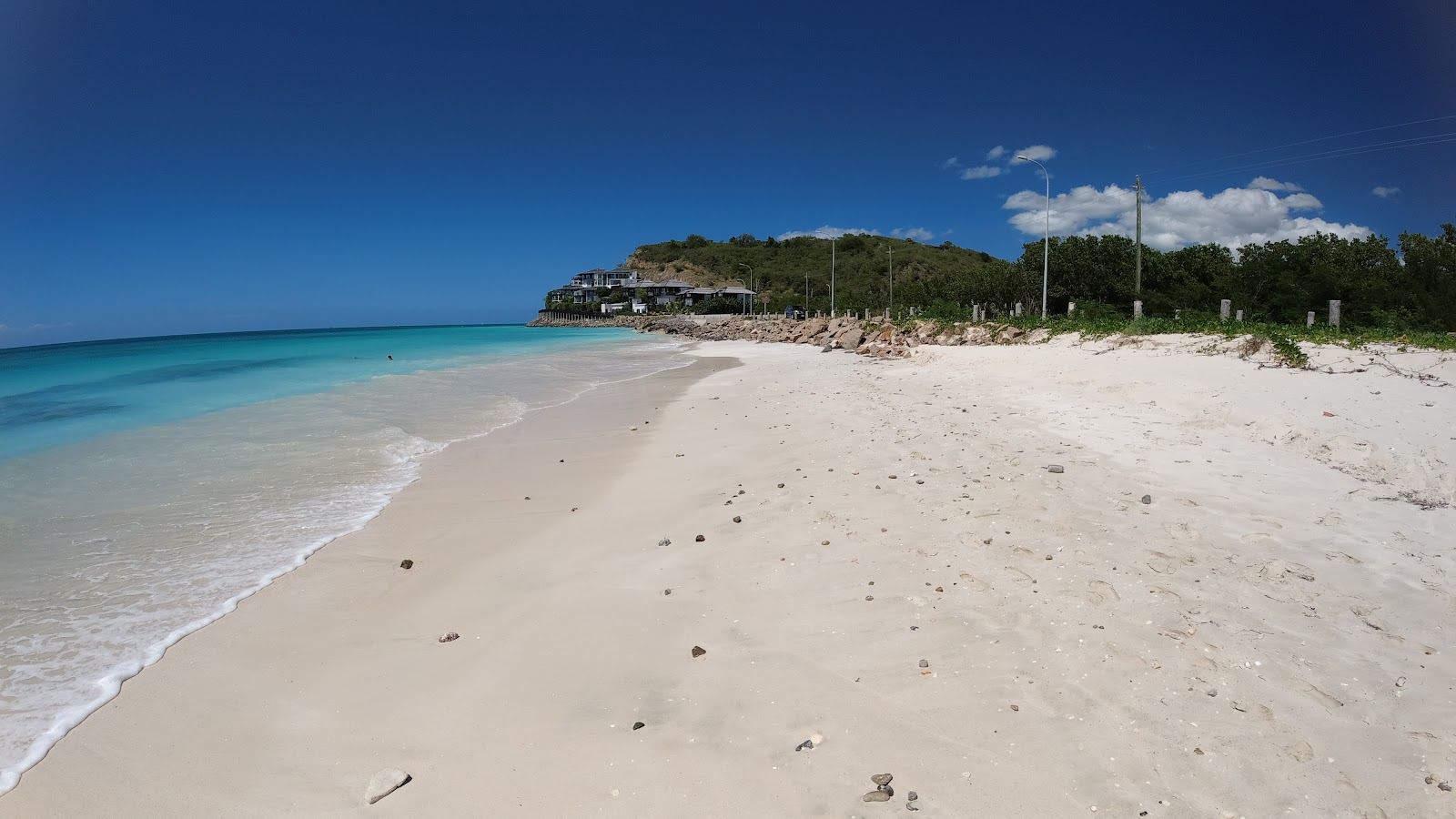 Clear shallow Caribbean water and soft sand at Darkwood Beach in Antigua with islands on the horizon
