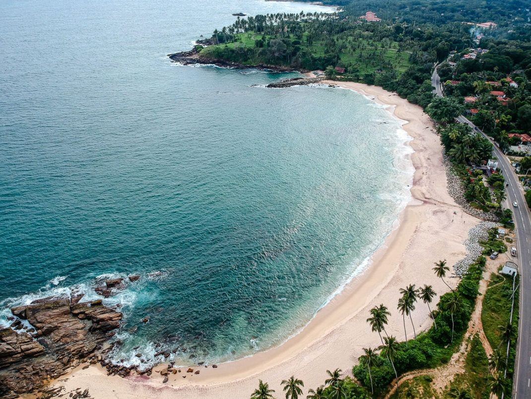 A horseshoe surf bay ringed with cafes and palms at Hiriketiya in southern Sri Lanka