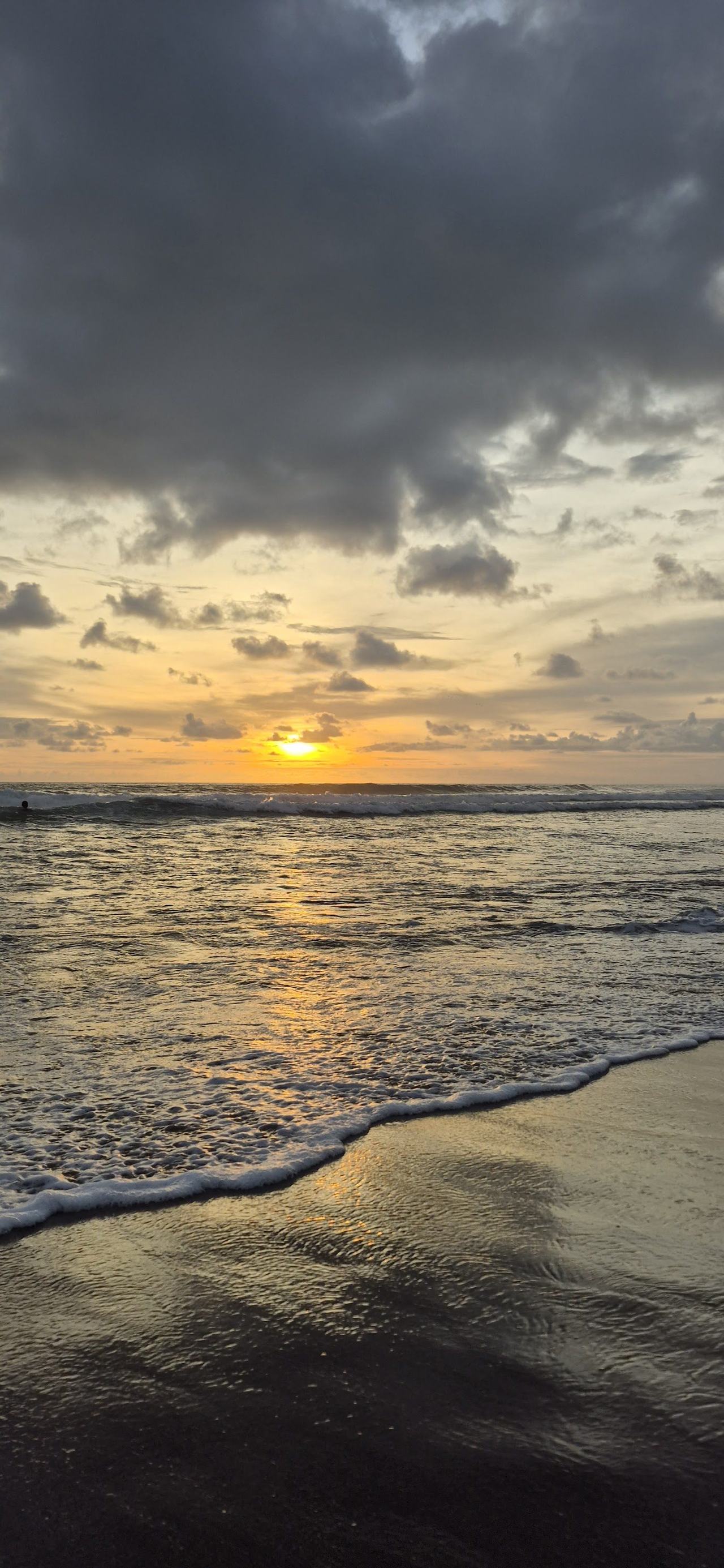 Surfers and dark volcanic sand at Echo Beach on the Canggu coast in Bali