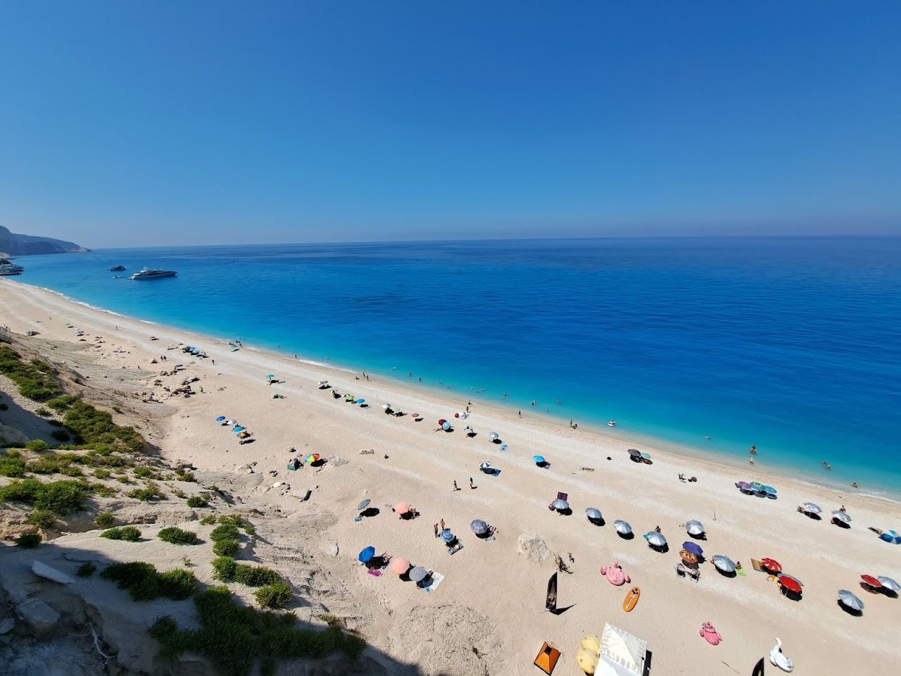 A long sweep of white pebbles and luminous turquoise water below tall cliffs at Egremni beach on the southwest coast of Lefkada