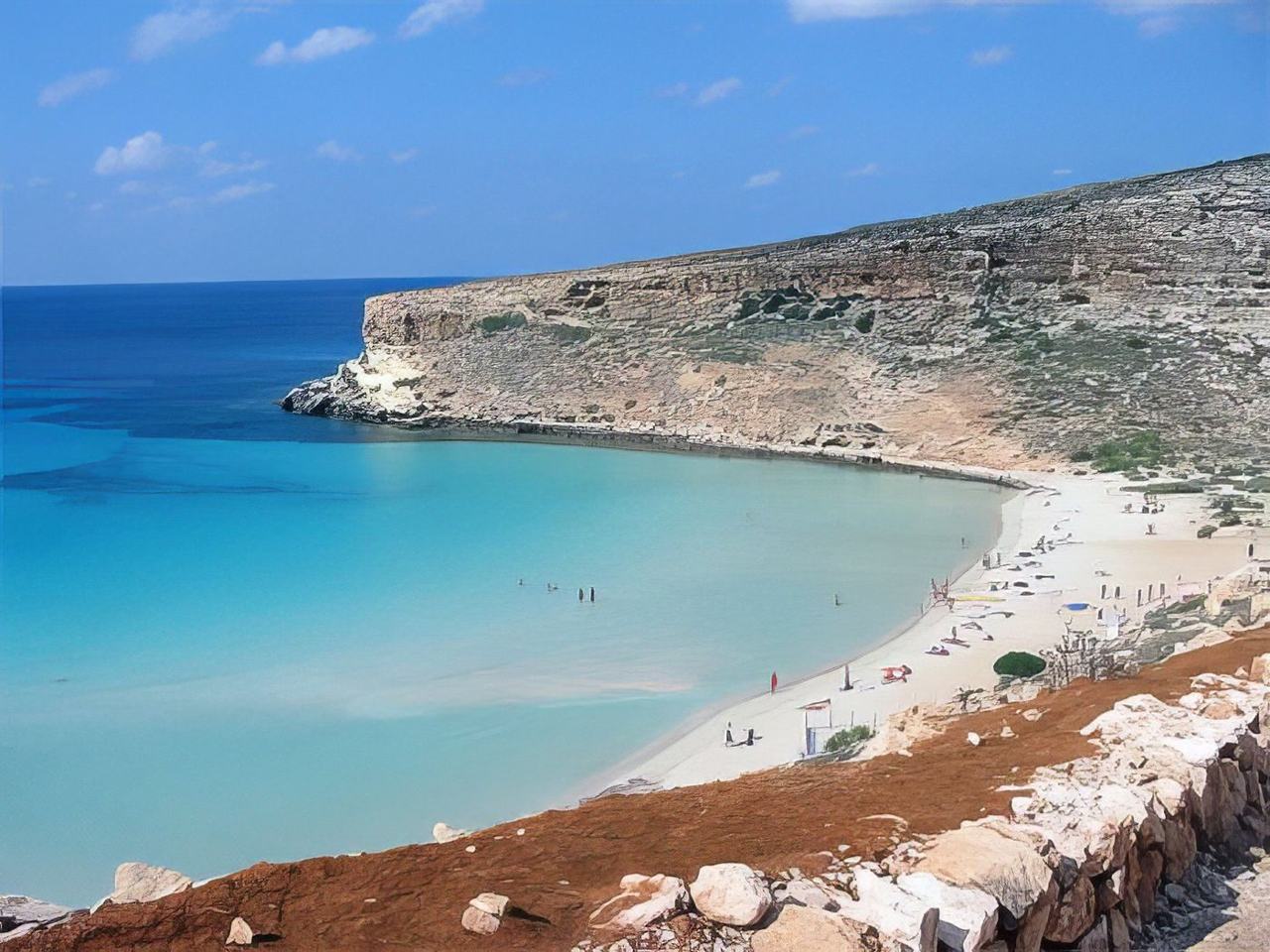 The pale sand curve and shallow lagoon of Rabbit Beach on Lampedusa