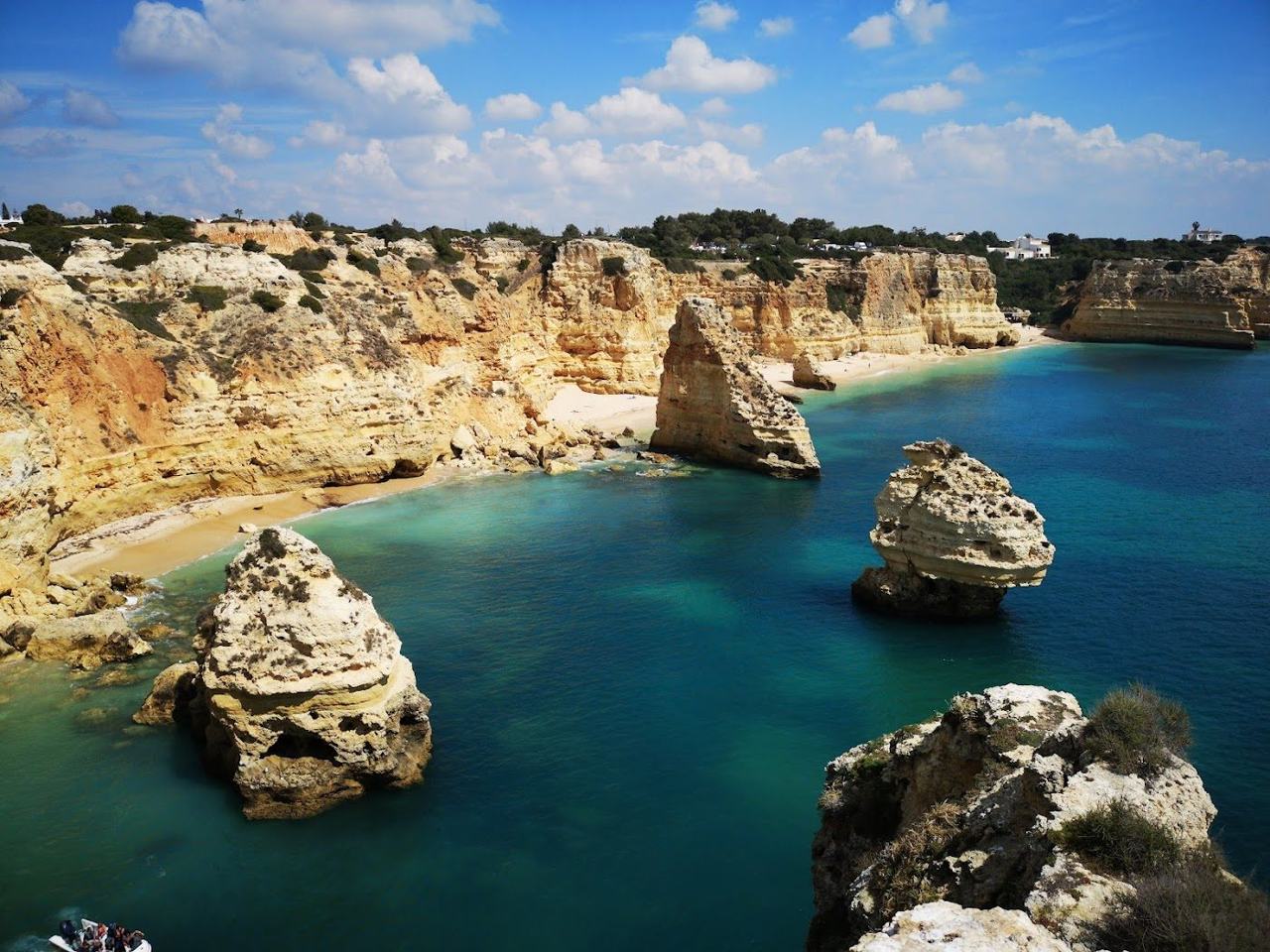 Golden cliffs and clear water above the sand at Praia da Marinha in the Algarve