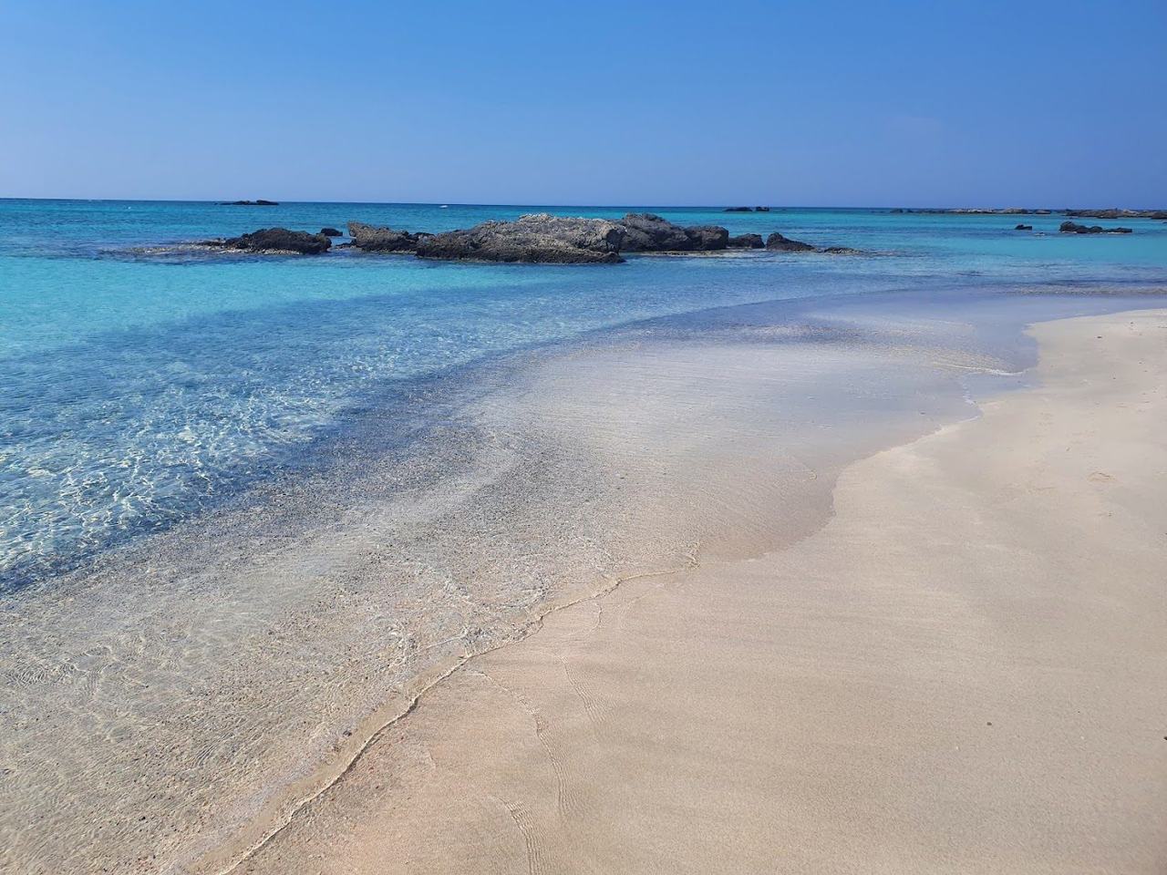 The blush pink shell sand and shallow turquoise lagoon at Elafonissi in Crete