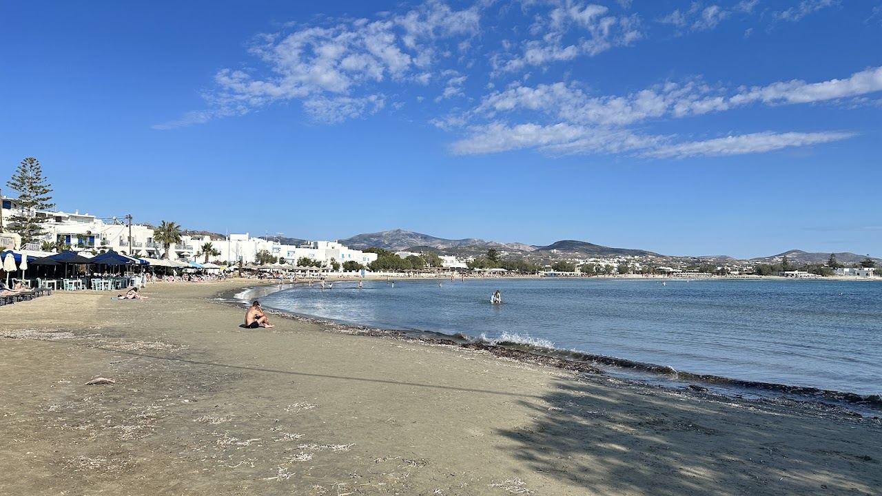 Children in the shallow calm water on the soft golden sand of a family beach near Naxos Town