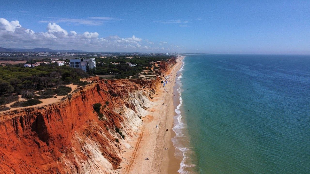 The long sand under ochre cliffs and gentle summer shelving of Falesia