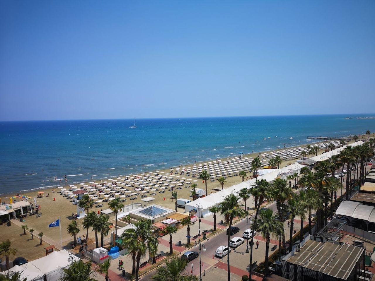 Palm trees, promenade and calm shallow water along the central Finikoudes beach in Larnaca Cyprus